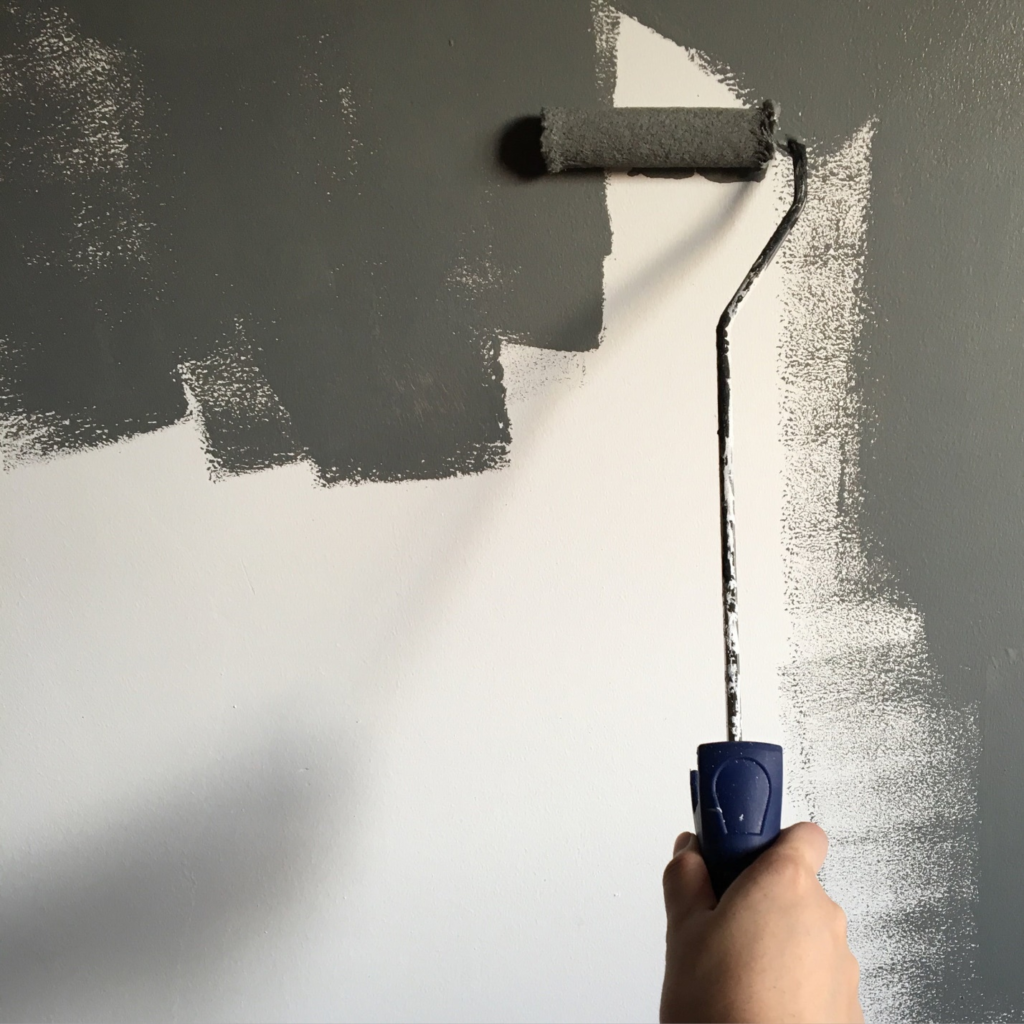 person painting a wall with brush